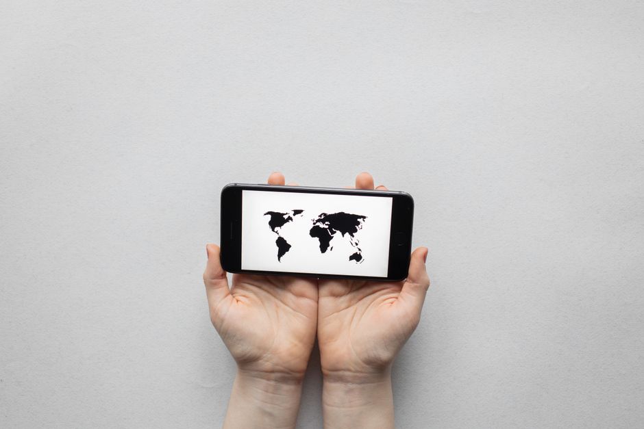 Hands holding a phone displaying a world map, representing carrier reach