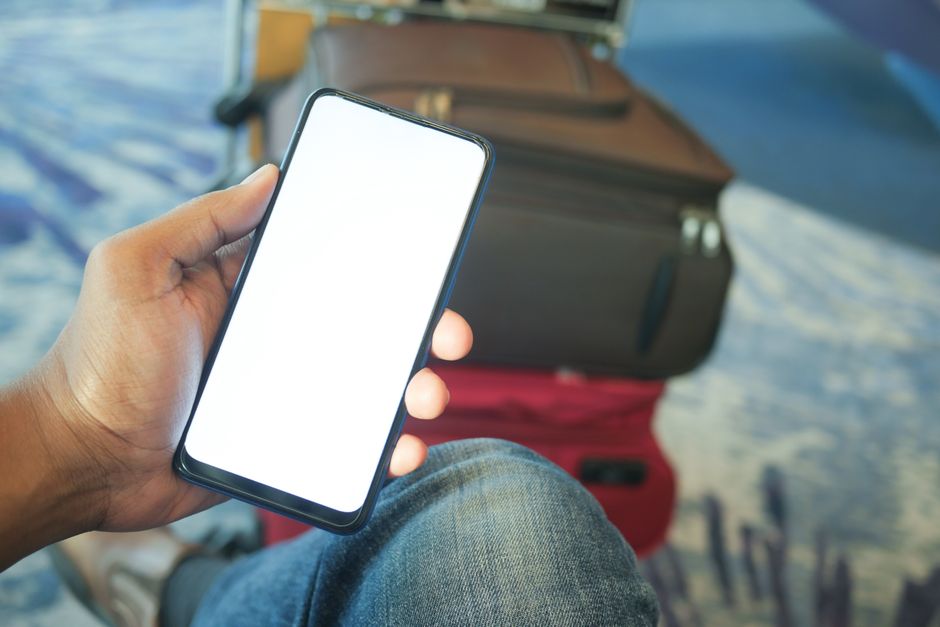 Traveler checking a phone next to luggage at the airport